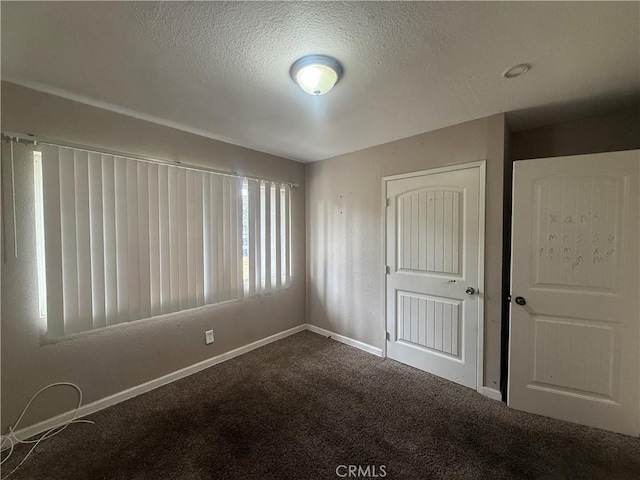carpeted empty room featuring a textured ceiling and baseboards