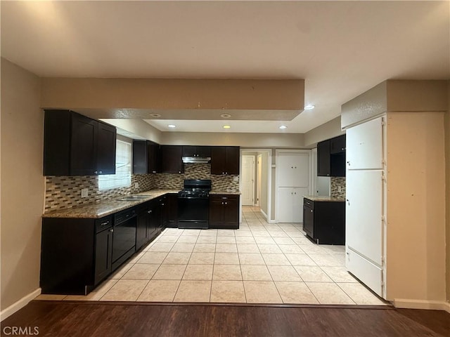 kitchen with black appliances, tasteful backsplash, dark cabinets, and a sink