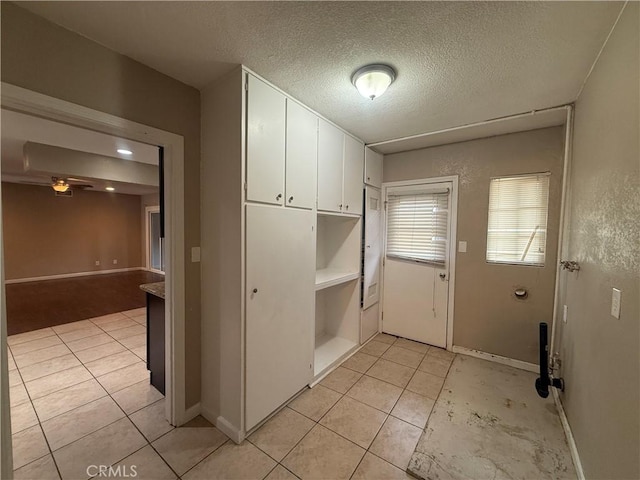washroom with a textured ceiling, baseboards, ceiling fan, and light tile patterned floors