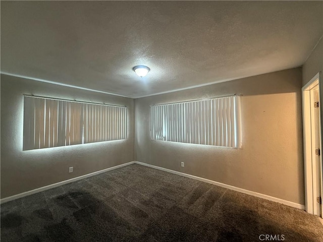 spare room featuring carpet flooring, a textured ceiling, and baseboards