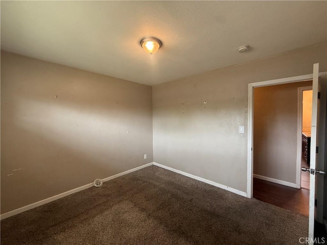 carpeted empty room featuring baseboards and a smoke detector