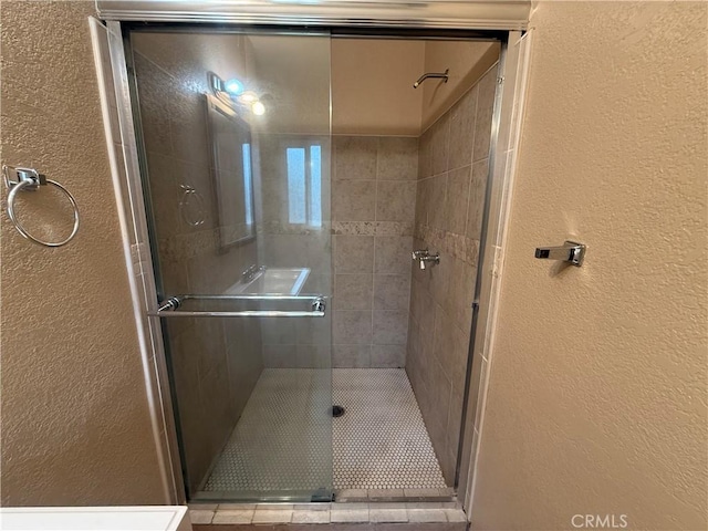 full bathroom with a textured wall and a stall shower