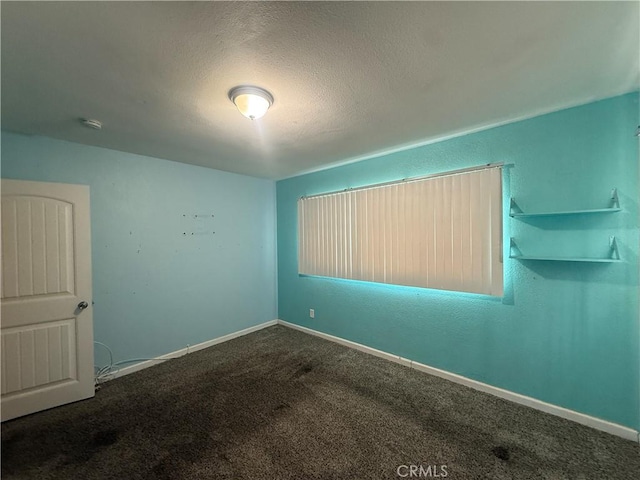 empty room featuring carpet flooring, a textured ceiling, a smoke detector, and baseboards