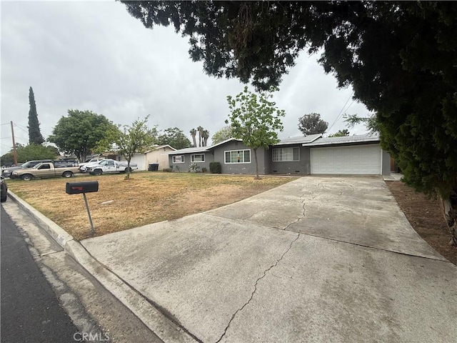 ranch-style house featuring driveway, an attached garage, and a front lawn