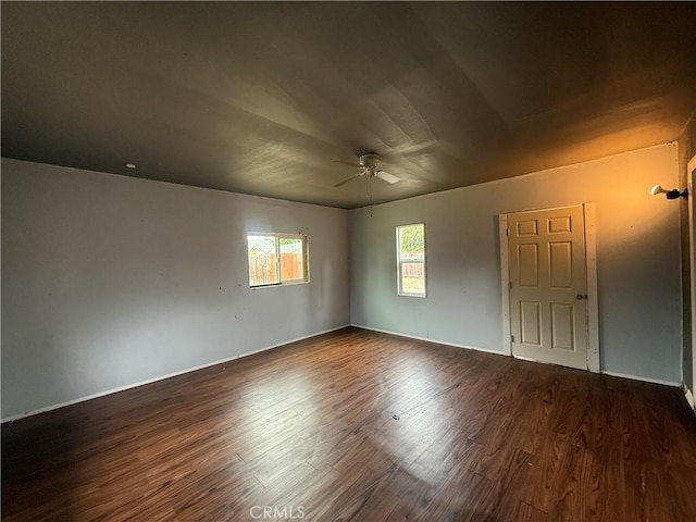 unfurnished room featuring ceiling fan, dark wood-style flooring, and baseboards