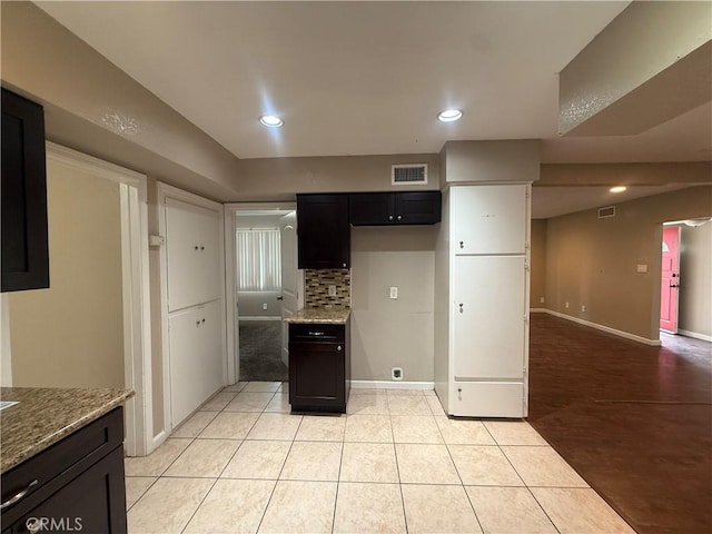 kitchen featuring baseboards, backsplash, light stone countertops, light tile patterned floors, and recessed lighting