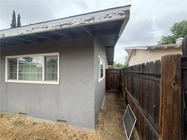 view of property exterior featuring fence, stucco siding, and crawl space