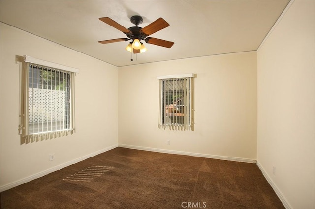 empty room with dark carpet, a ceiling fan, and baseboards