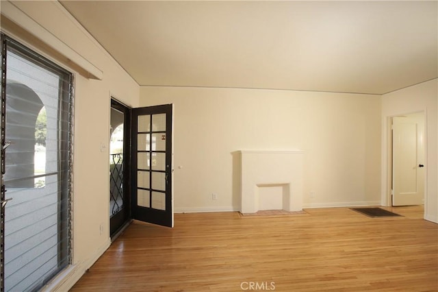 unfurnished room with wood finished floors, healthy amount of natural light, and baseboards