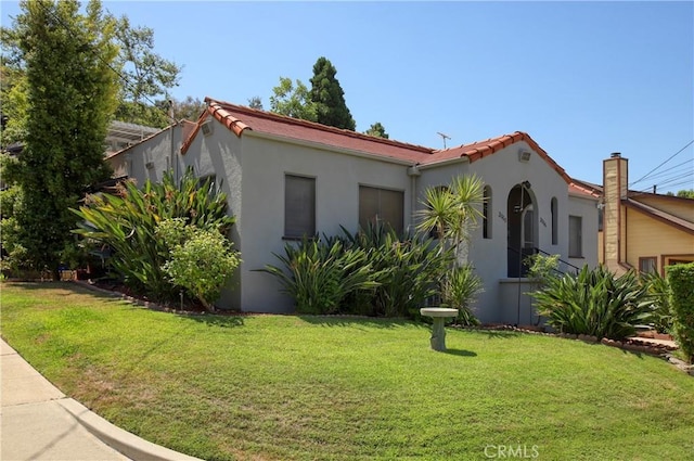 mediterranean / spanish home featuring a front lawn, stucco siding, an attached garage, and a tiled roof