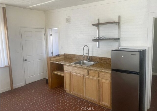 66229 8th St, Desert Hot Springs, CA 92240 - kitchen with freestanding refrigerator, open shelves, a sink, brick patterned flooring, and brown cabinetry