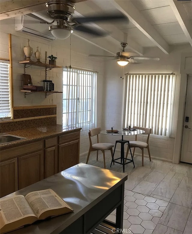 66229 8th St, Desert Hot Springs, CA 92240 - kitchen with ceiling fan, beamed ceiling, plenty of natural light, dark countertops, and brown cabinetry
