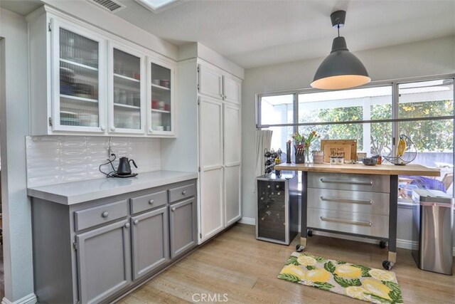 1398 Carissa St, Upland, CA 91784 - bar with light wood-type flooring, wine cooler, tasteful backsplash, and hanging light fixtures