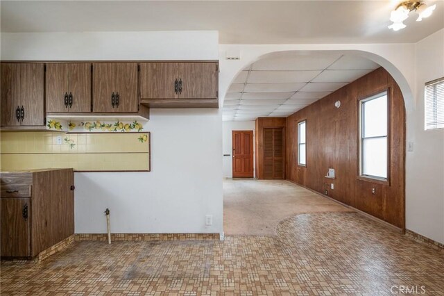 kitchen featuring arched walkways, baseboards, and a drop ceiling