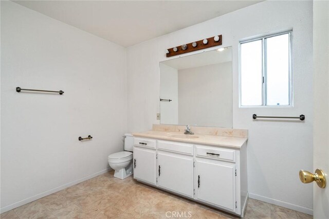 bathroom with toilet, vanity, and baseboards