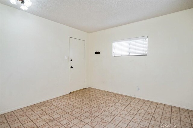 unfurnished room featuring a textured ceiling and baseboards