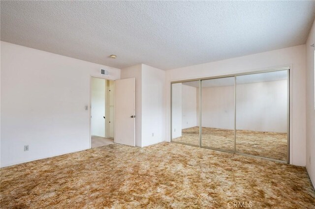 unfurnished bedroom with carpet floors, a textured ceiling, and a closet