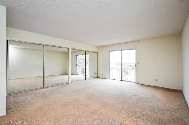 unfurnished bedroom featuring access to exterior, carpet floors, and multiple closets