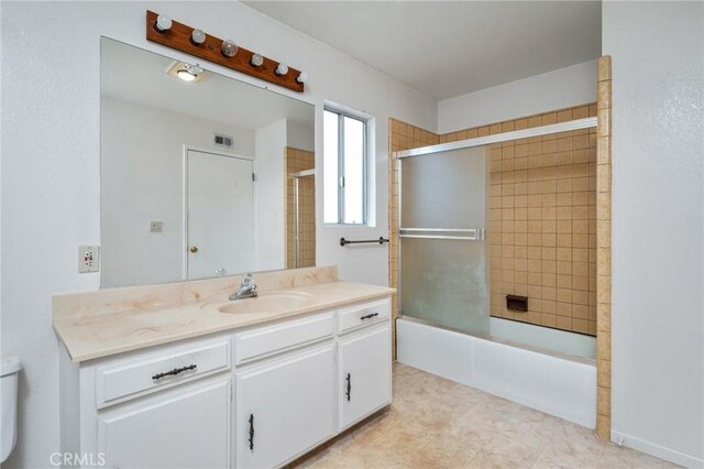 full bath featuring vanity, bath / shower combo with glass door, and toilet