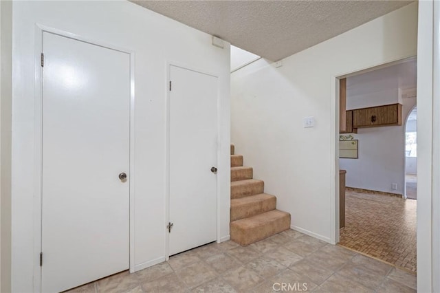 stairs featuring a textured ceiling and baseboards
