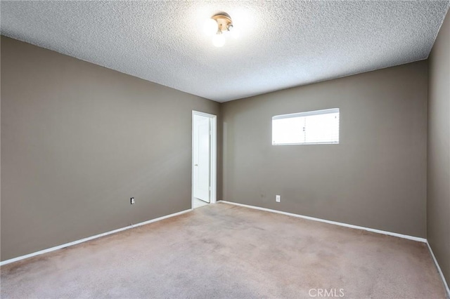 spare room featuring carpet, baseboards, and a textured ceiling