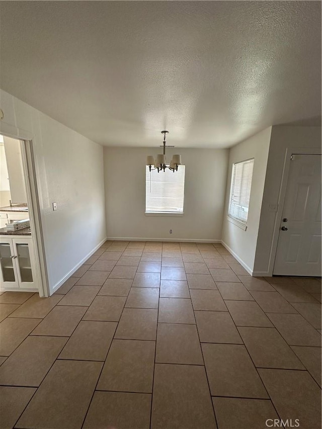 44226 2nd St E, Lancaster, CA 93535 - unfurnished dining area with a chandelier, a textured ceiling, light tile patterned floors, and baseboards