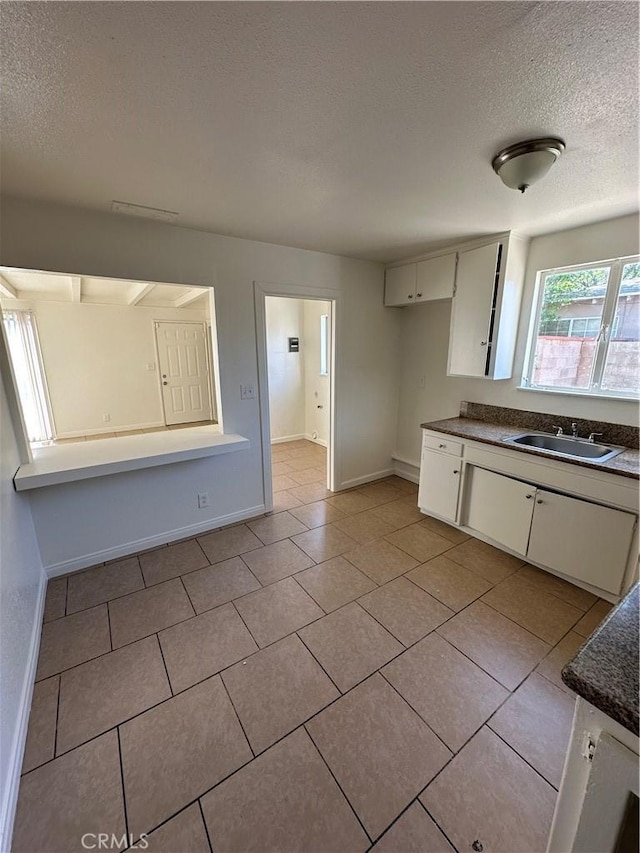 44226 2nd St E, Lancaster, CA 93535 - kitchen with a sink, dark countertops, a textured ceiling, baseboards, and light tile patterned floors