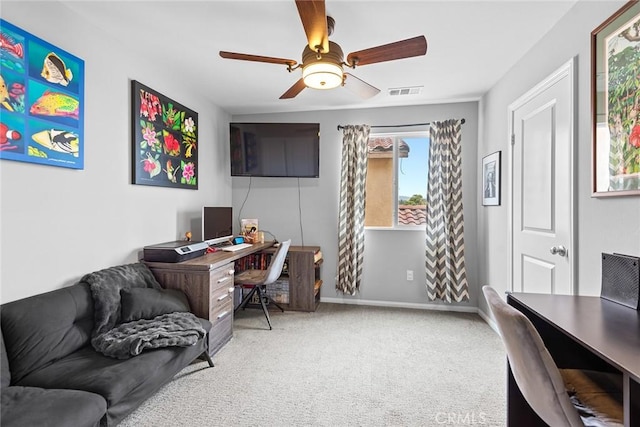 carpeted office space featuring ceiling fan and baseboards