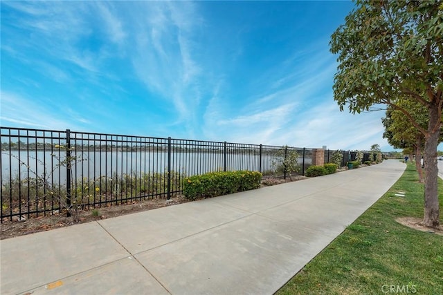 view of community with fence and a water view