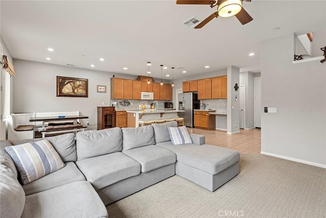 living room featuring recessed lighting, ceiling fan, baseboards, light tile patterned flooring, and light carpet