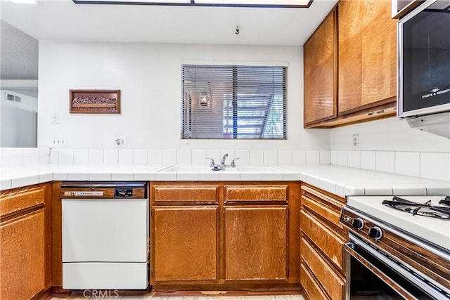 16512 Blackbeard Ln Unit 102, Huntington Beach, CA 92649 - kitchen featuring dishwasher, a sink, and brown cabinets
