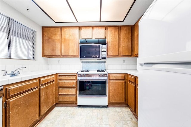 16512 Blackbeard Ln Unit 102, Huntington Beach, CA 92649 - kitchen featuring freestanding refrigerator, gas stove, and brown cabinets