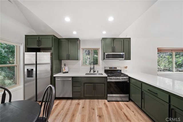 kitchen with green cabinets, stainless steel appliances, a sink, lofted ceiling, and plenty of natural light