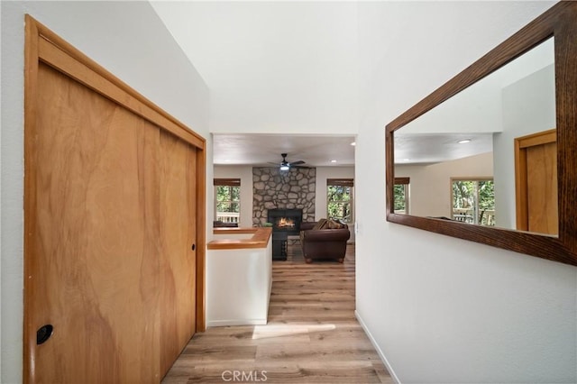 hallway with light wood finished floors, recessed lighting, plenty of natural light, and baseboards