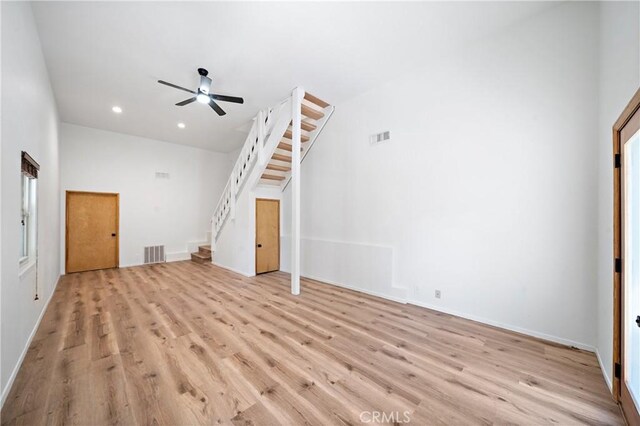 unfurnished living room with stairway, light wood-style flooring, a ceiling fan, baseboards, and recessed lighting