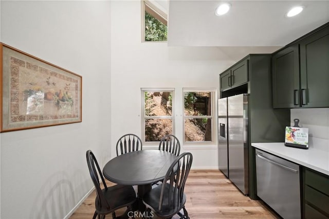 dining area with healthy amount of natural light, light wood-type flooring, baseboards, recessed lighting, and a high ceiling