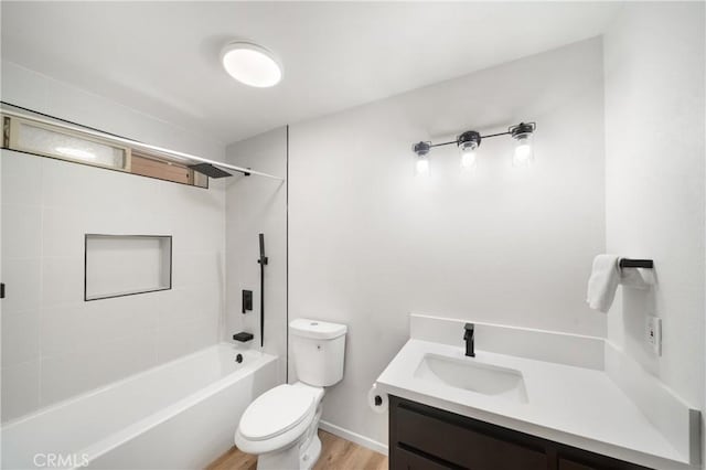bathroom featuring toilet, vanity, wood finished floors, and washtub / shower combination