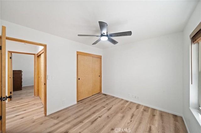 unfurnished bedroom with light wood-style floors, a closet, baseboards, and ceiling fan