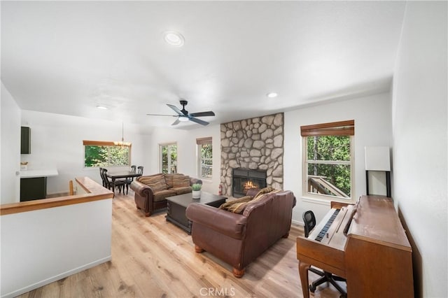 living room with light wood-type flooring, a stone fireplace, recessed lighting, and a ceiling fan