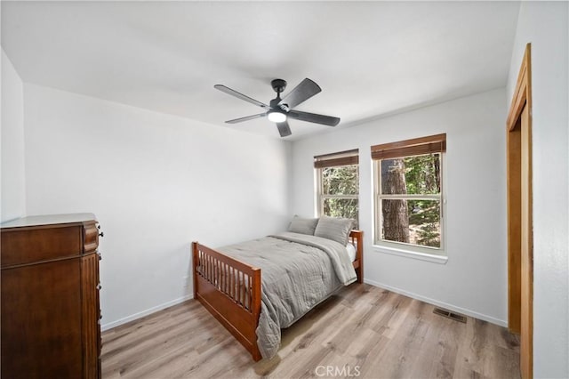 bedroom with light wood-style flooring, a ceiling fan, and baseboards