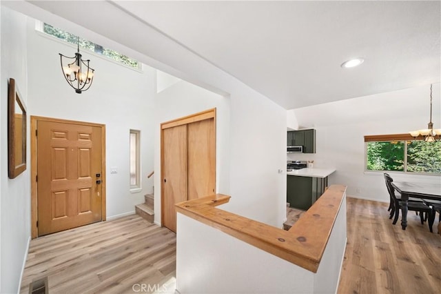 entrance foyer featuring a chandelier, light wood-type flooring, stairs, baseboards, and recessed lighting