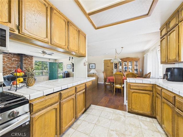 40170 Hillsborough Loop, Oakhurst, CA 93644 - kitchen with a wood stove, stainless steel appliances, open floor plan, a peninsula, and brown cabinets