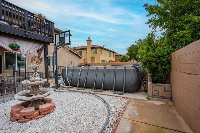 view of patio with an outdoor pool and fence