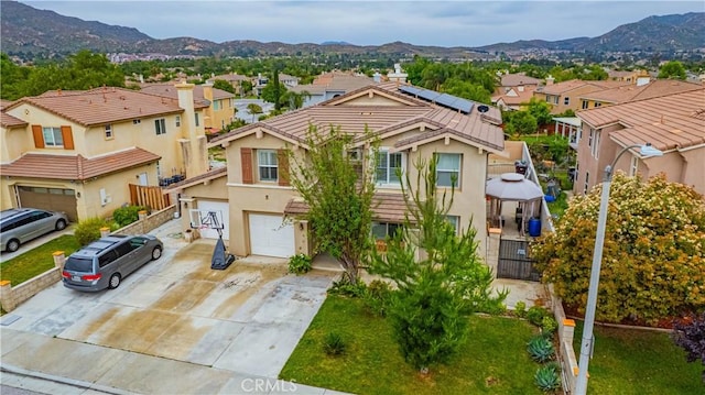 view of front of home featuring a residential view, an attached garage, driveway, and a mountain view