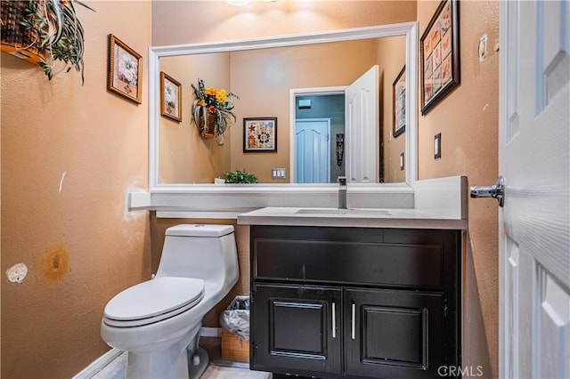 half bathroom with toilet, vanity, and baseboards