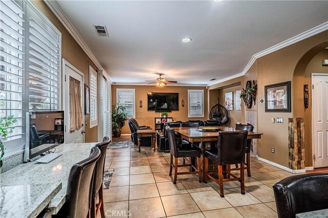 dining area featuring healthy amount of natural light, arched walkways, crown molding, light tile patterned flooring, and ceiling fan