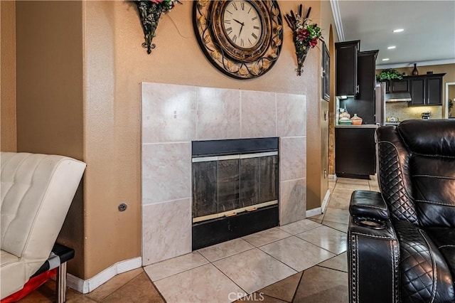 living room with light tile patterned flooring, a tiled fireplace, baseboards, crown molding, and recessed lighting