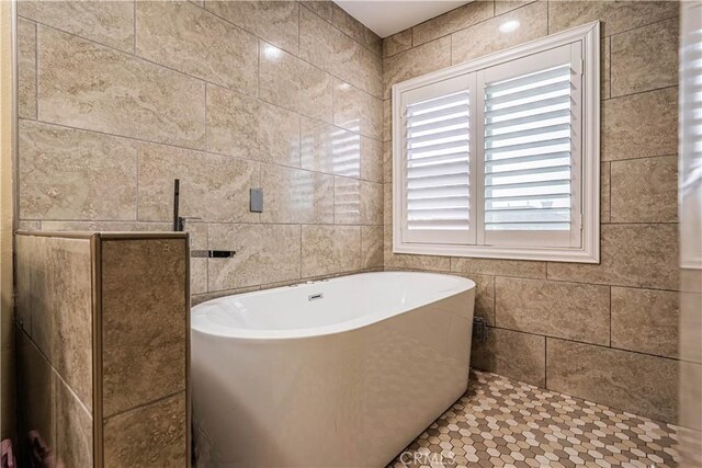 bathroom with a soaking tub and tile walls