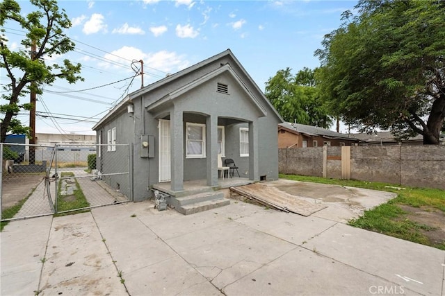 rear view of house featuring stucco siding, a gate, fence, and a patio