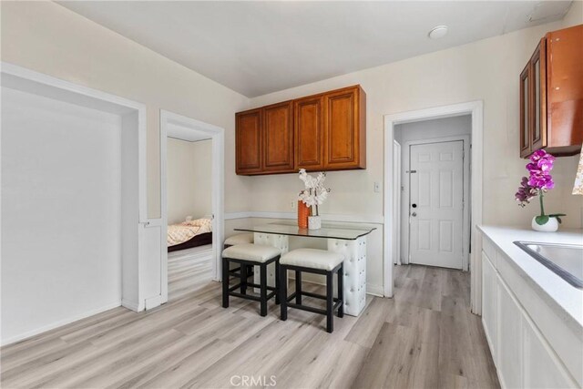 kitchen with light wood-style flooring, light countertops, brown cabinets, and a sink